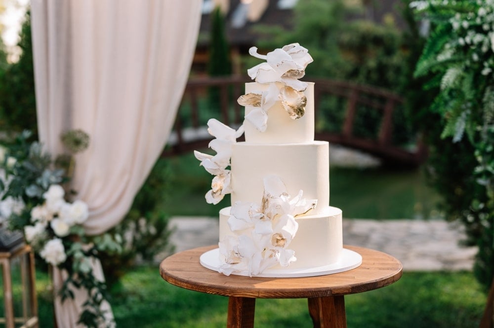 Elegant three-tier white wedding cake with floral accents on a decorated table