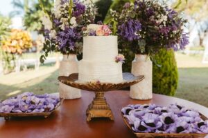 Elegant three-tier white wedding cake with floral accents on a decorated table