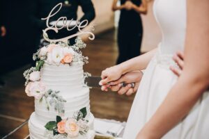 Bride and groom cutting a three-tier wedding cake with silver knife during their reception