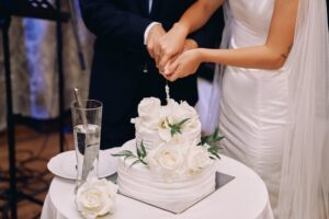 Bride and groom cutting a three-tier wedding cake with silver knife during their reception
