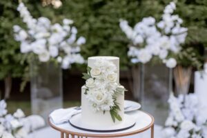 Bride and groom cutting a three-tier wedding cake with silver knife during their reception